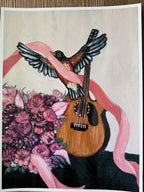 A rectangular art print  depicting a robin bird with spread wings resting on a wooden guitar, wrapped in a pink ribbon, with a bouquet of pink and purple flowers at the lower left, shown against a light background with a white border.